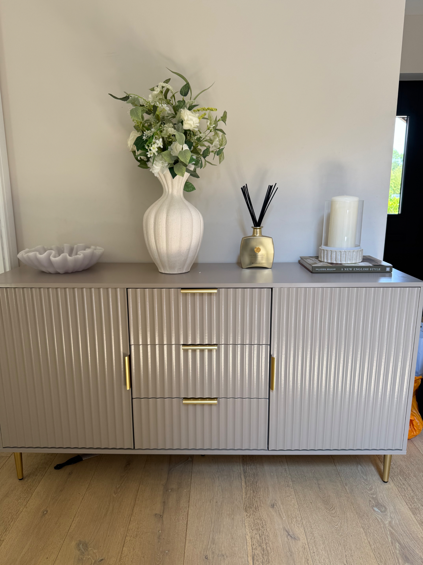 Fluted taupe sideboard with brass handles, white vase and diffuser