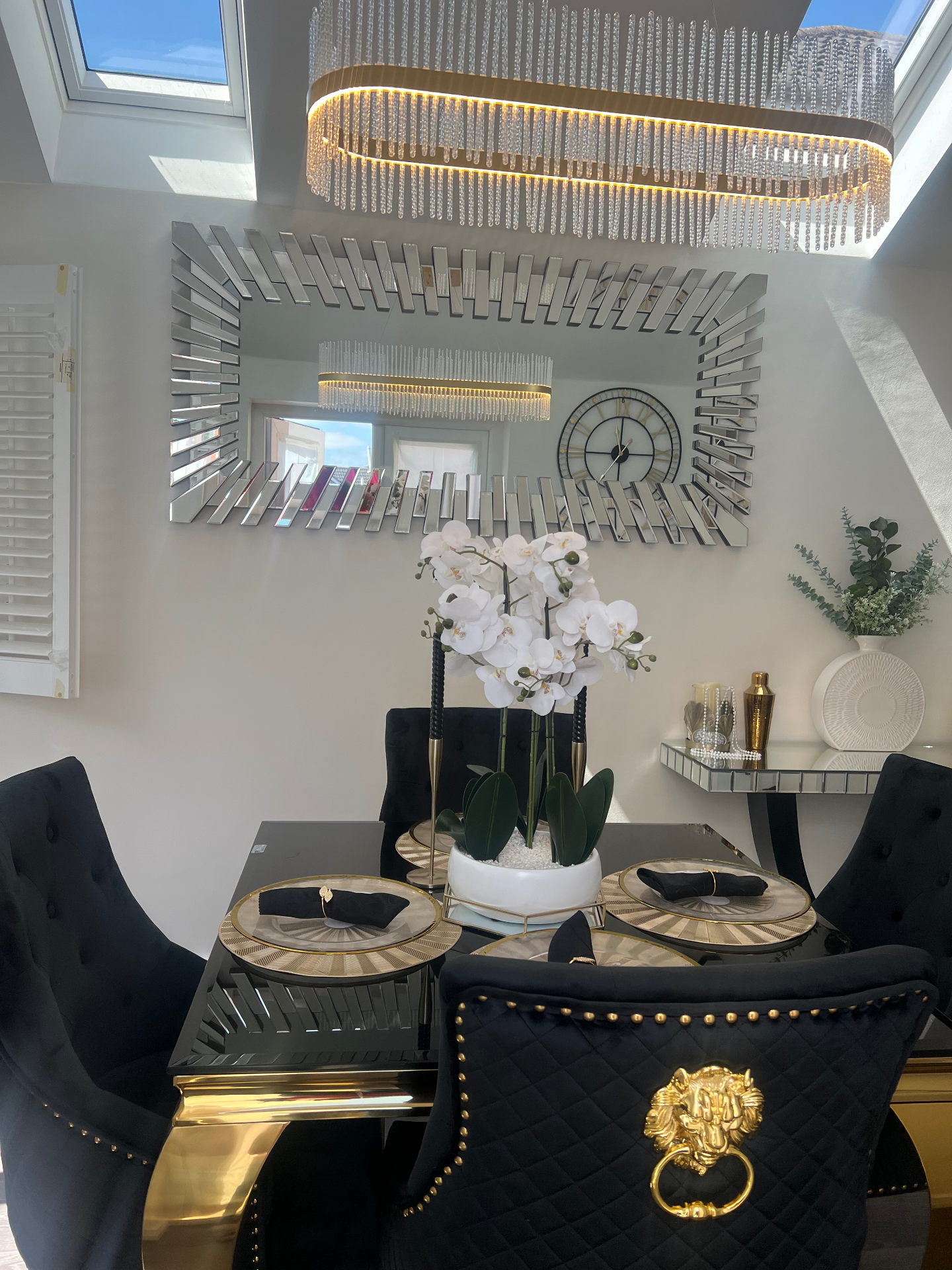 Black and gold dining room with crystal chandelier and mirrored feature wall