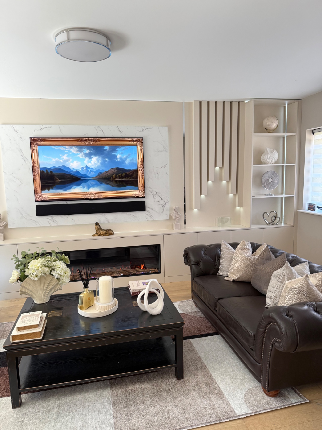 Living room with marble media wall, framed art TV and Chesterfield sofa