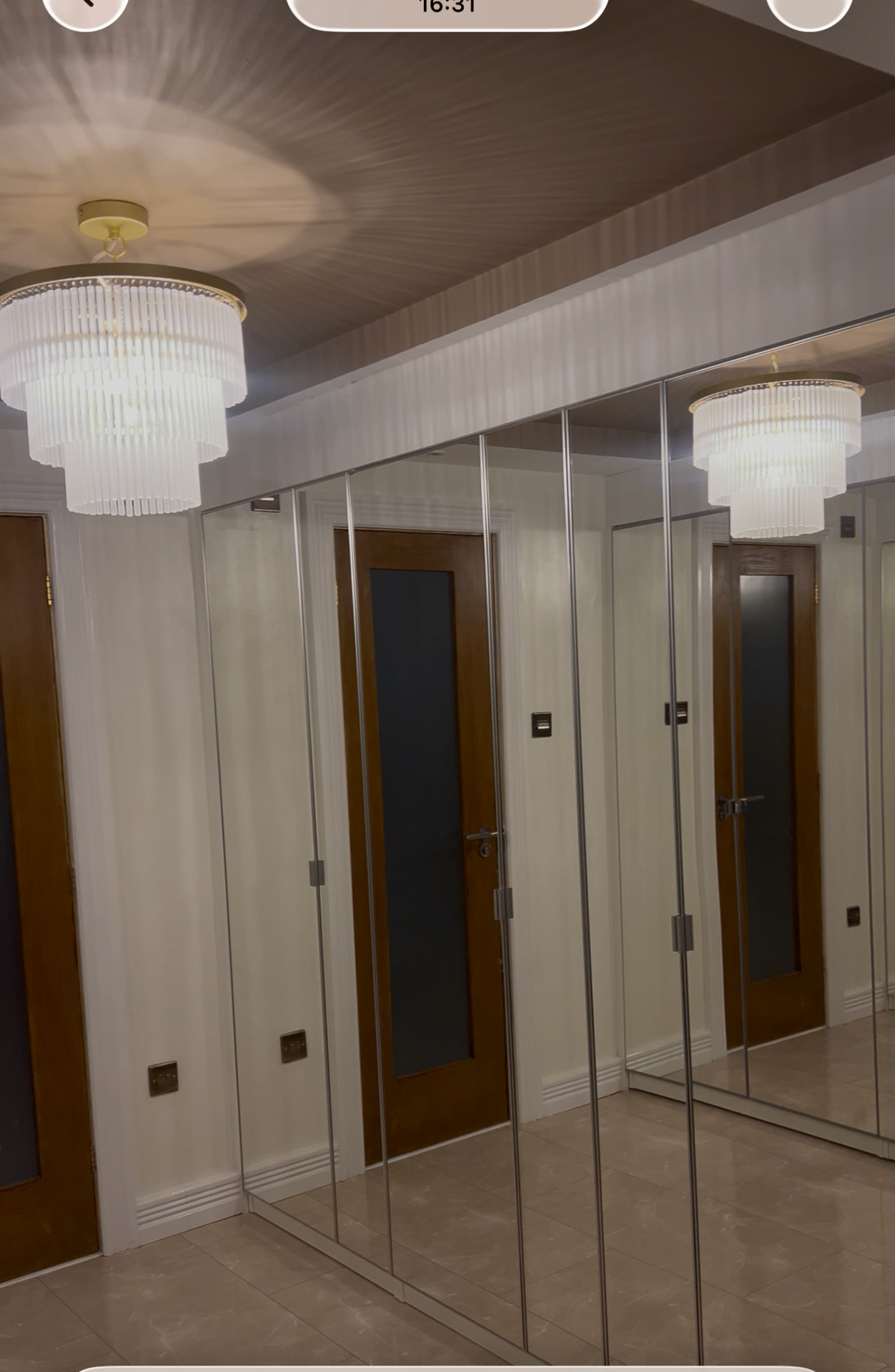 Mirrored hallway wardrobes reflecting layered chandeliers and panelled walls