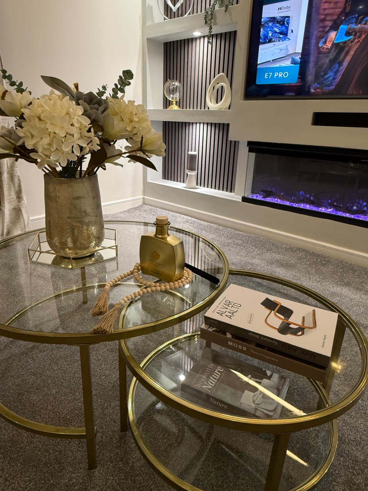 Glass and brass nesting tables styled with gold diffuser, design books and white blossoms