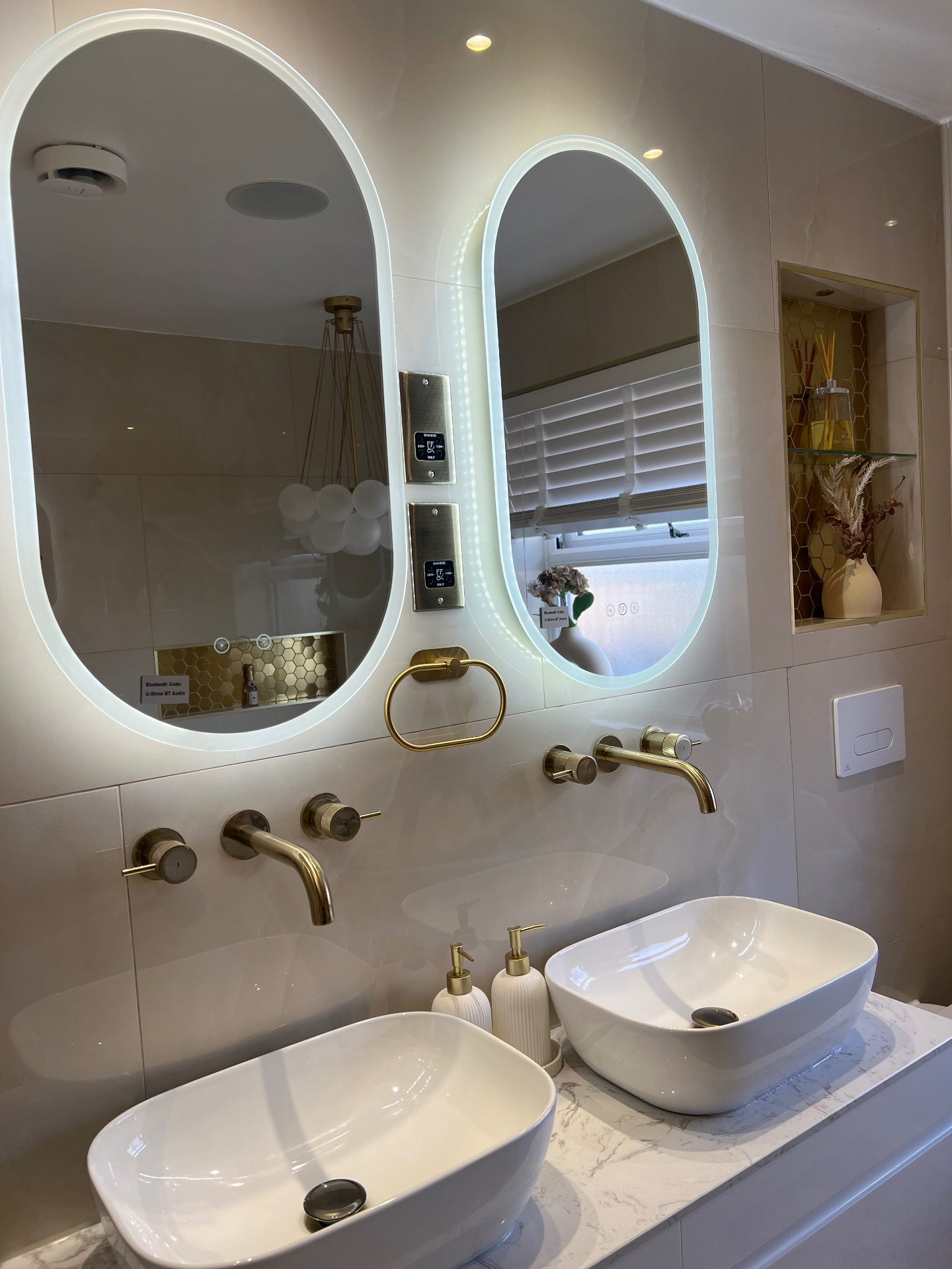 Ensuite with twin oval LED mirrors, brushed brass taps and marble vanity