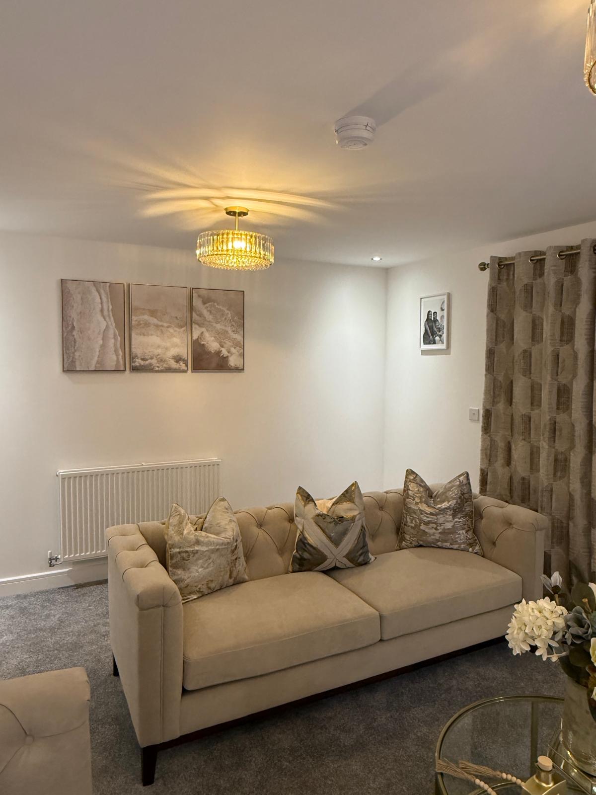 Champagne velvet tufted sofa with layered metallic cushions and framed prints