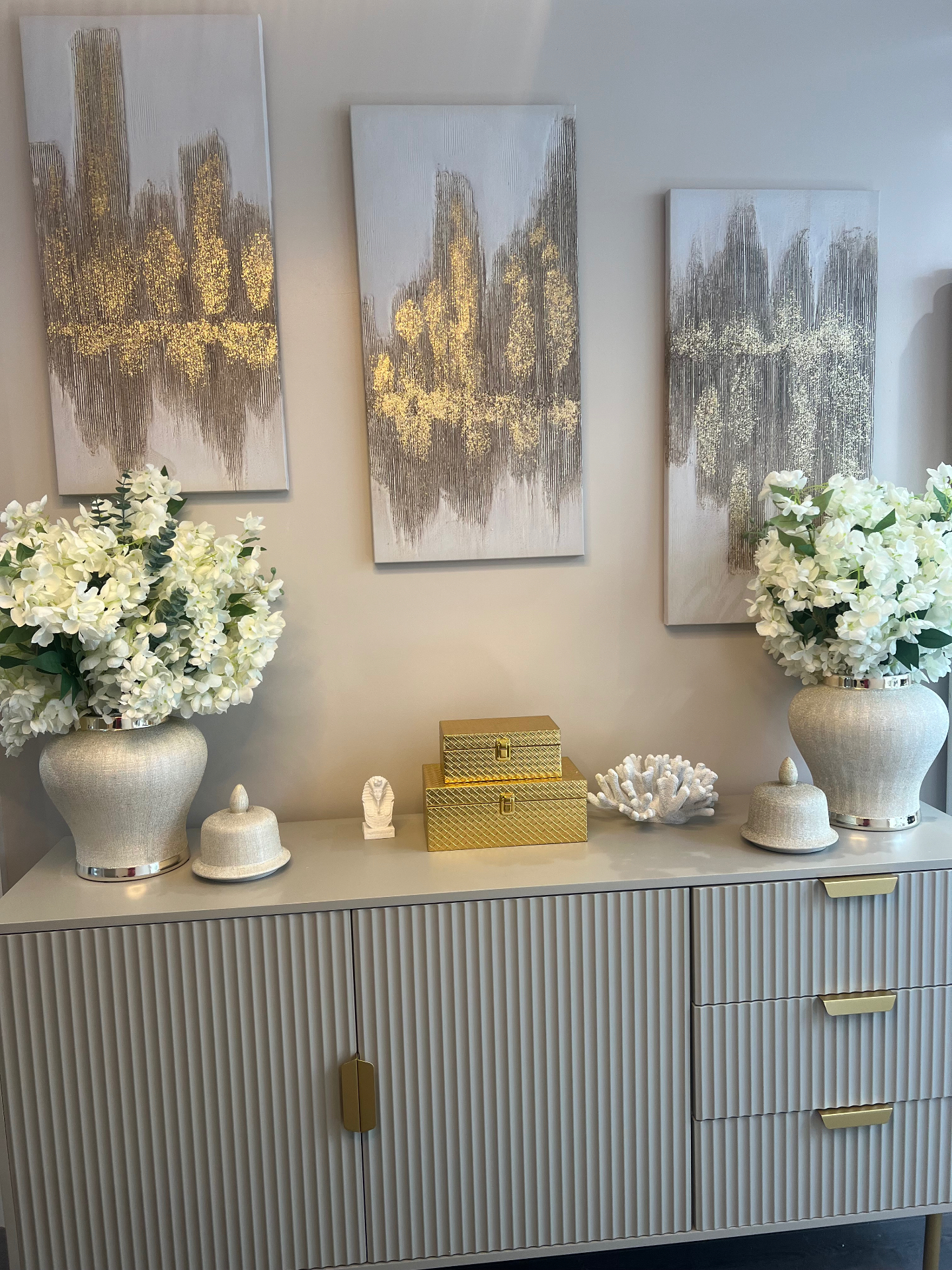 Fluted sideboard with twin hydrangea urns and gold-flecked canvases