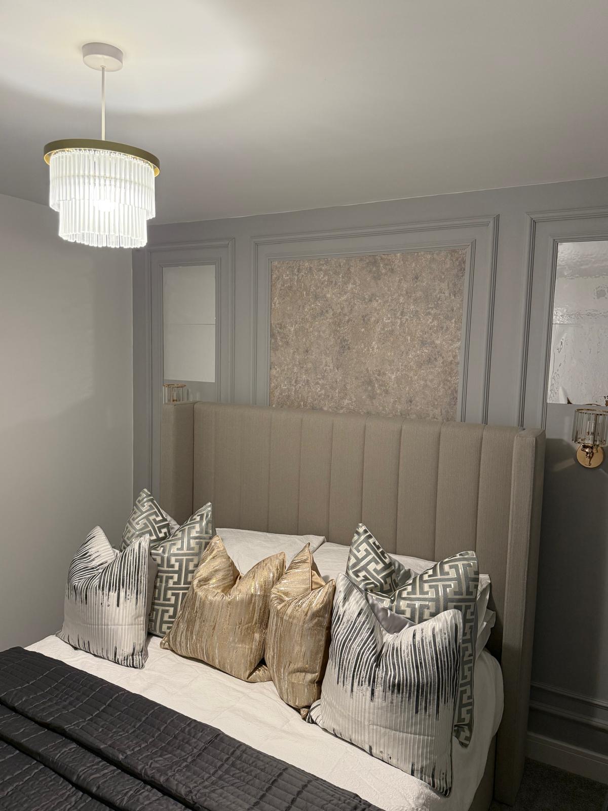 Principal bedroom with panelled walls, tall linen headboard and layered cushions