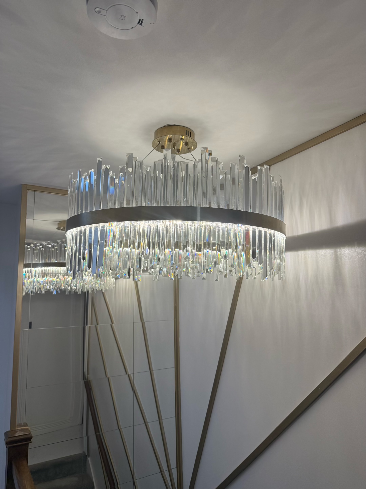 Crystal drum chandelier catching light above a brushed brass floor lamp